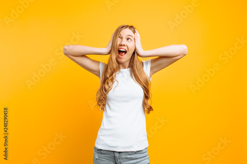 Portrait of an annoyed woman covering her ears and screaming from a terrible noise, on a yellow background