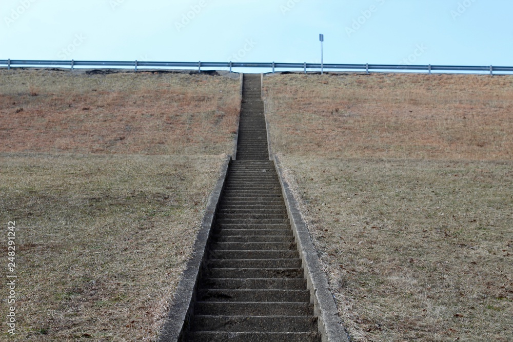 The cement steps up the green grass hill landscape.