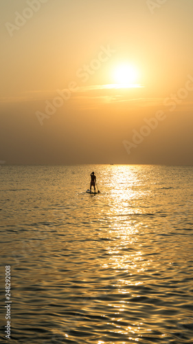 Stand up paddle board at sunset on the Phu Quoc beach Vietnam,travel concept,beach activity,Person stand up paddle boarding at dusk beautiful sunset colors © Hryhorii