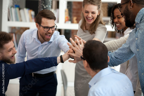 Excited motivated multi-ethnic team people give high five in office photo