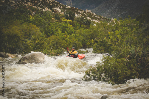 Close up image of a white water kayak paddler riding white water on a mountain river