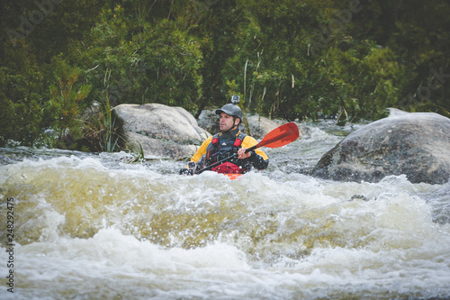Close up image of a white water kayak paddler riding white water on a mountain river © Dewald