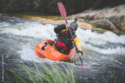 Close up image of a white water kayak paddler riding white water on a mountain river photo