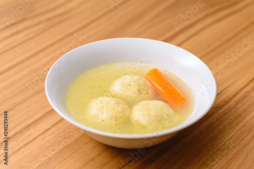 Traditional matzoh ball (kneidlach) soup.White bowl with authentic matzo ball chicken taste hot soup ( bouillon ) tradition Jewish food for Passover and every day.