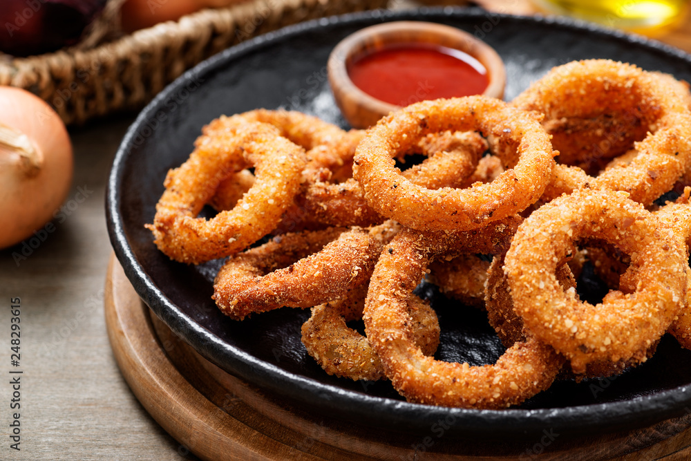 Delicious golden battered, breaded and deep fried crispy onion rings with ketchup. Delicious golden battered, breaded and deep fried crispy onion rings with ketchup.