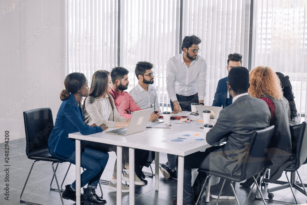 Indian corporate trainer is teaching interns, while supervising brainstorming disscussion at conference room Indian corporate trainer is teaching interns, while supervising brainstorming disscussion at conference room