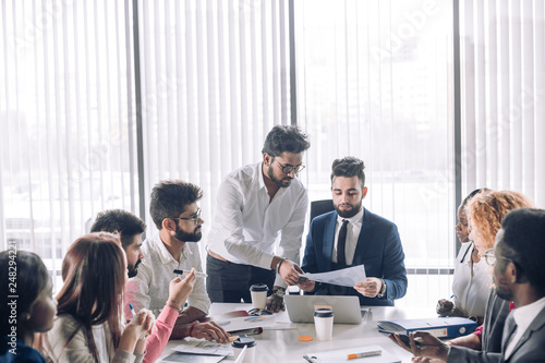 Relaxed informal IT business company meeting. Team leader in formal suit discussing new ways of vision and ideas of income increase with subordinates. Startup business and entrepreneurship concept photo