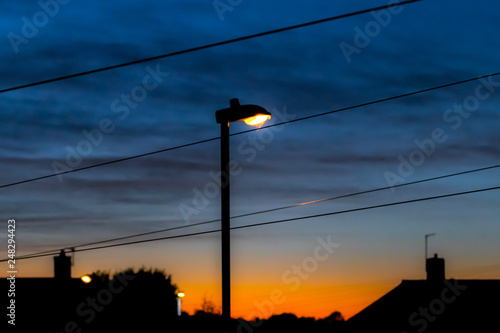 Illuminating orange/white street light in foreground with dramatic and moody sky with clouds.