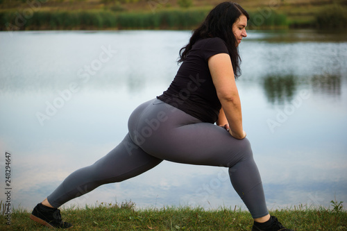 Overweight woman do morning training near lake