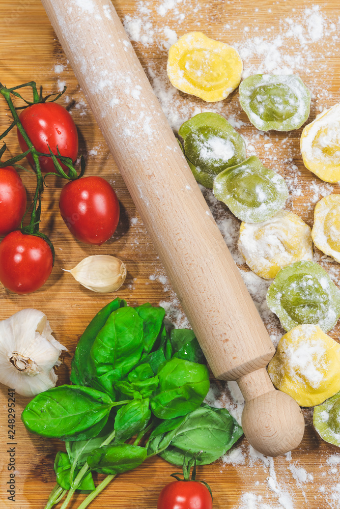 Homemade fresh Italian ravioli pasta on wood table with flour, basil,tomatoes,background,top view. Homemade fresh Italian ravioli pasta on wood table with flour, basil,tomatoes,background,top view.