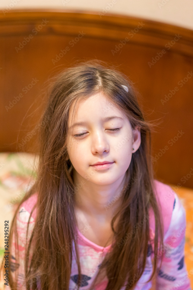 Cute little girl stretching her arms happily with a smile from waking up in her bed. child sleepy yawning in bed. Sleepy little girl on the bed. vertical photo. close up. Cute little girl stretching her arms happily with a smile from waking up in her bed. child sleepy yawning in bed. Sleepy little girl on the bed. vertical photo. close up.