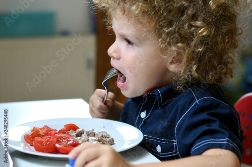 Junge steckt sich Gabel mit Fleisch in den Mund
