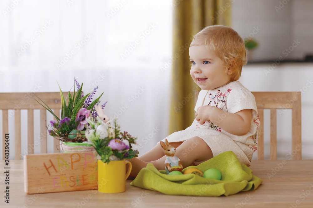 Happy child sitting at the table and holding easter egg Happy child sitting at the table and holding easter egg