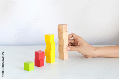 Hand stacking business and finance growth chart wooden cubes on white background.
