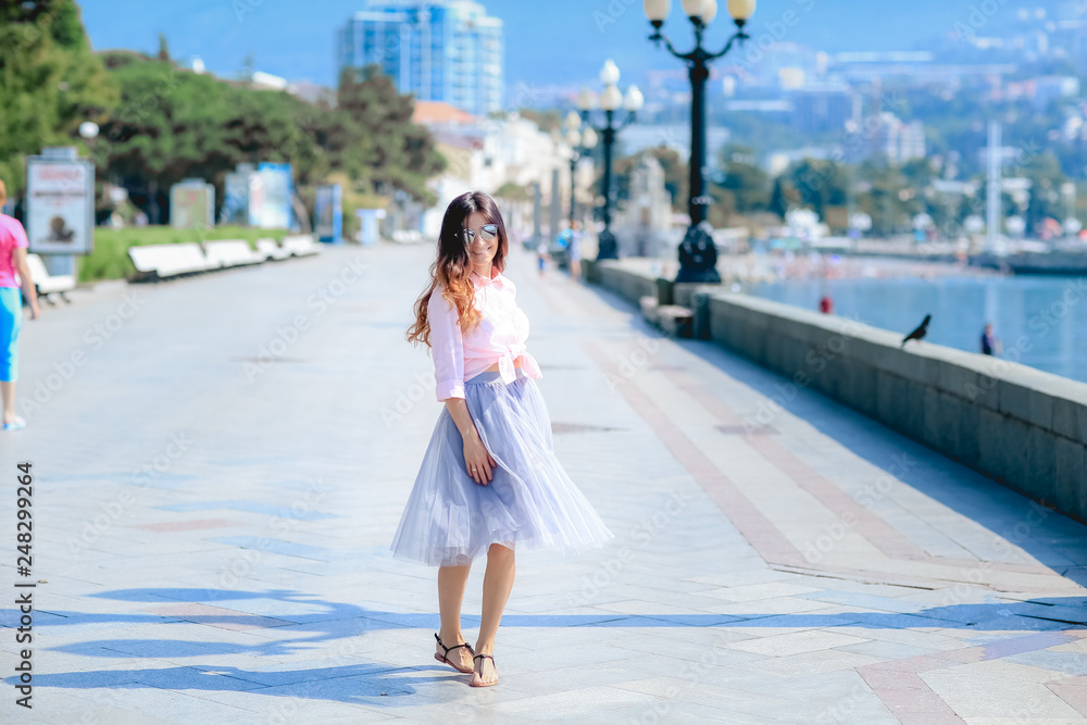 Girl walking along the seafront in dress in hot summer day Girl walking along the seafront in dress in hot summer day