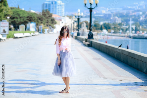 Girl walking along the seafront in dress in hot summer day