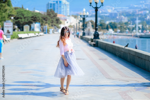 Girl walking along the seafront in dress in hot summer day