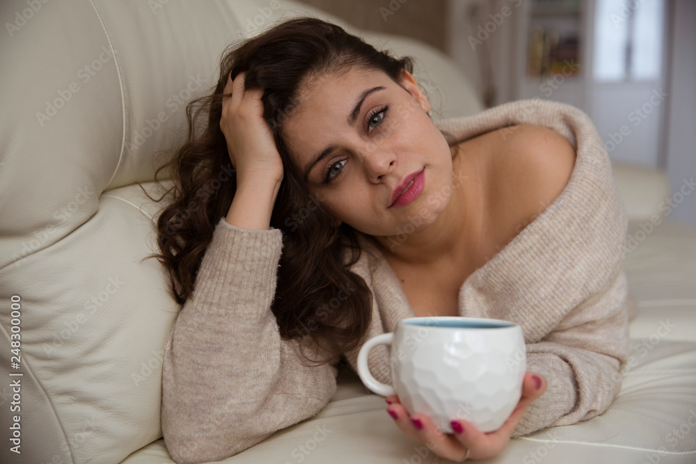 Girl lying on the sofa and drinking coffee