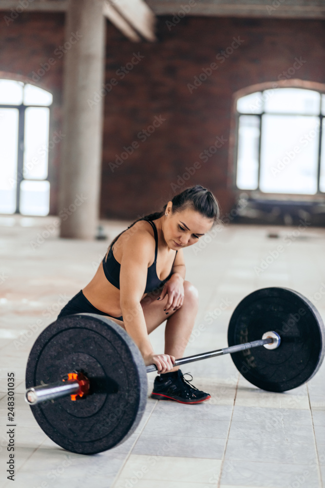 full length side view photo of a slim girl sitting near the barbell. relaxation,pensive female athlete looking at the barbell and preparing to lift it full length side view photo of a slim girl sitting near the barbell. relaxation,pensive female athlete looking at the barbell and preparing to lift it
