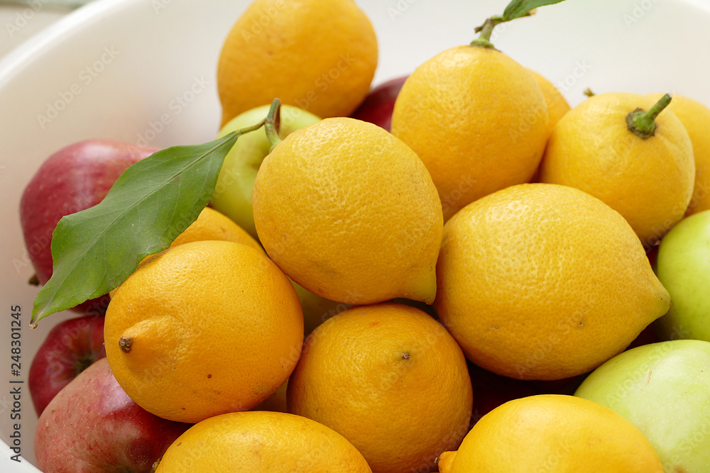 lemon on a leaf, a large amount of natural lemon in a container, yellow lemons,