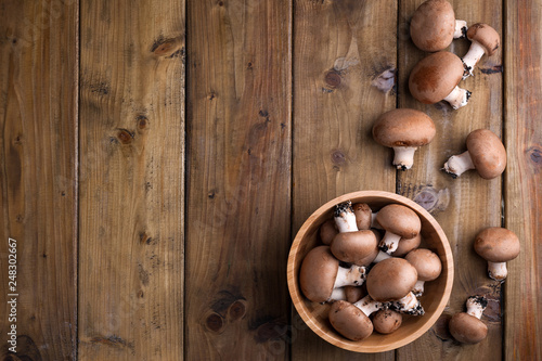 Champignon mushrooms, sacking mat and spices on wooden background. Wooden dishes. Photo in a rustic style. Place for text.