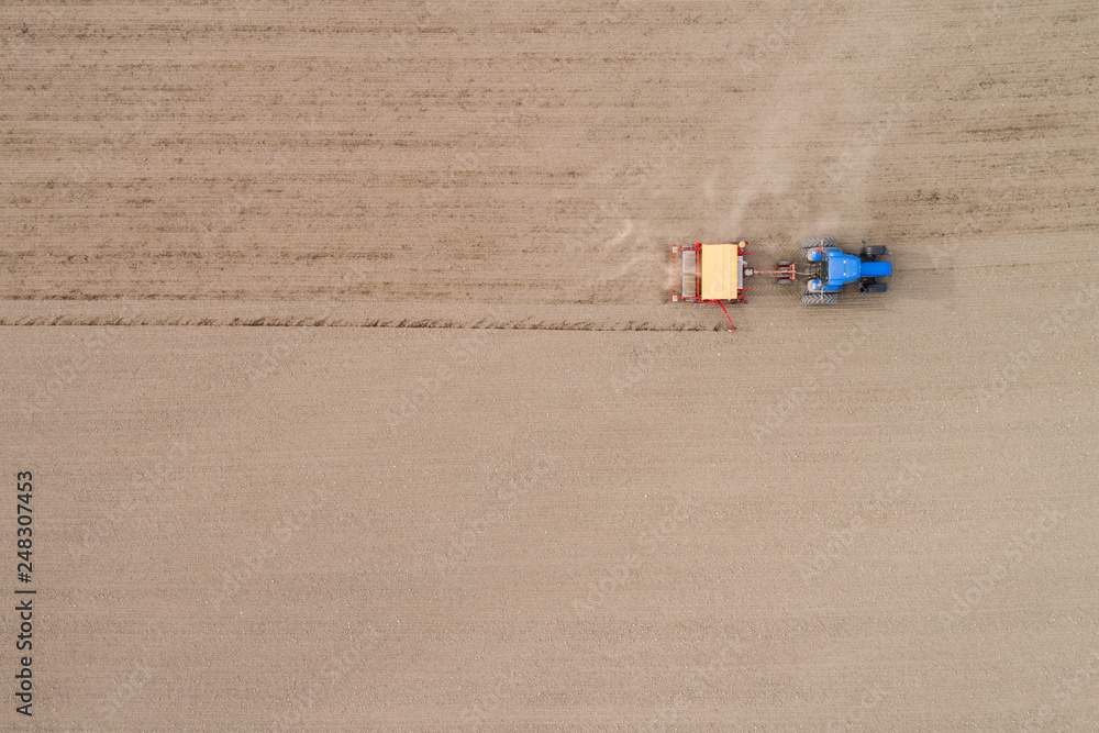 Aerial view the tractor plows the spring field. Spring season of agricultural works at farmlands. Aerial view the tractor plows the spring field. Spring season of agricultural works at farmlands.