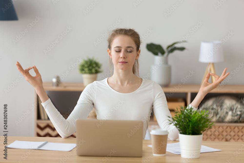 Young woman student taking break meditating at home office desk Young woman student taking break meditating at home office desk