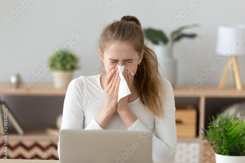 Ill young woman caught cold sneezing wiping running nose photo