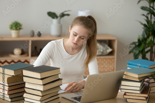 Teen girl preparing for exam writing essay coursework in notebook photo