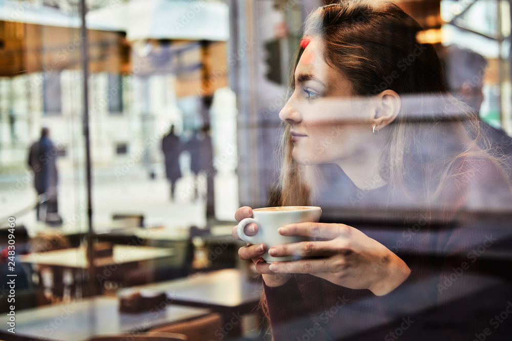 Girl daydreaming while holds a coffee cup at local coffee shop Girl daydreaming while holds a coffee cup at local coffee shop