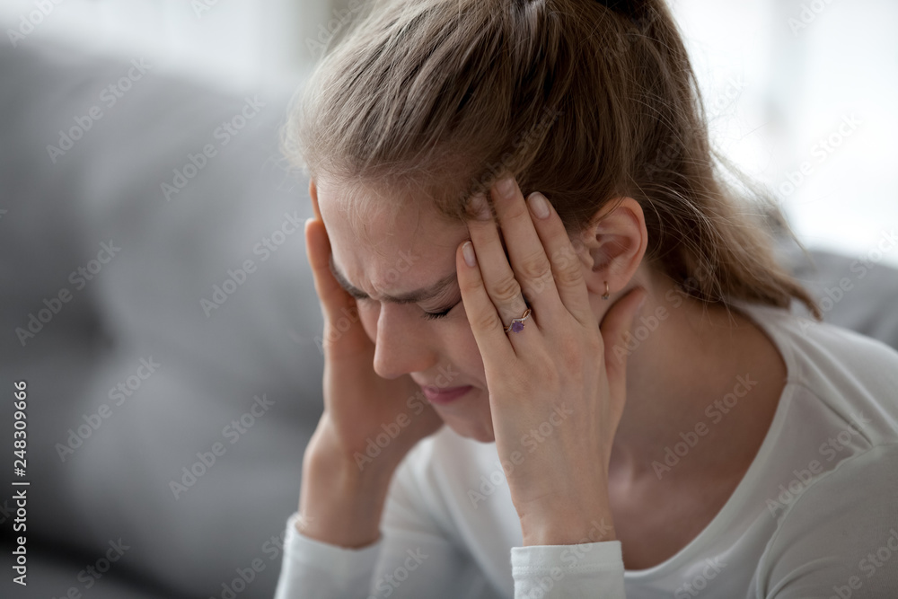Stressed young sick woman having strong terrible headache massaging temples Stressed young sick woman having strong terrible headache massaging temples