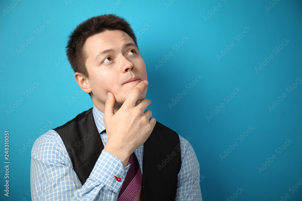 Young businessman in suit on blue background is thinking over question or problem. Young businessman in suit on blue background is thinking over question or problem.