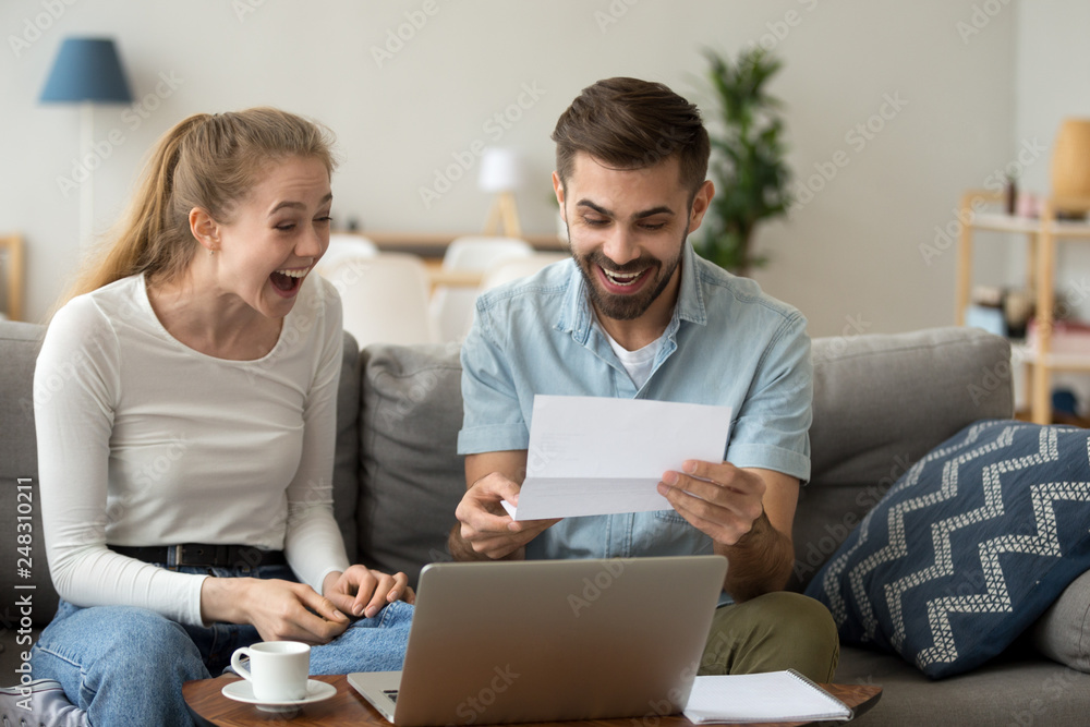 Excited couple screaming with joy reading good news in letter