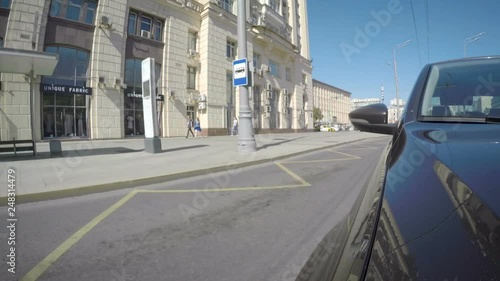 Car moves along the city street on sunny summer day. Front view from the car body.