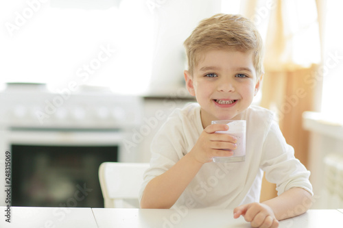 Kid or blonde happy boy eating at table. Childhood and happiness, independence. Breakfast, morning, family. Small boy child eat banana and drink milk. Healthy food and vitamin. dieting, vegetarian