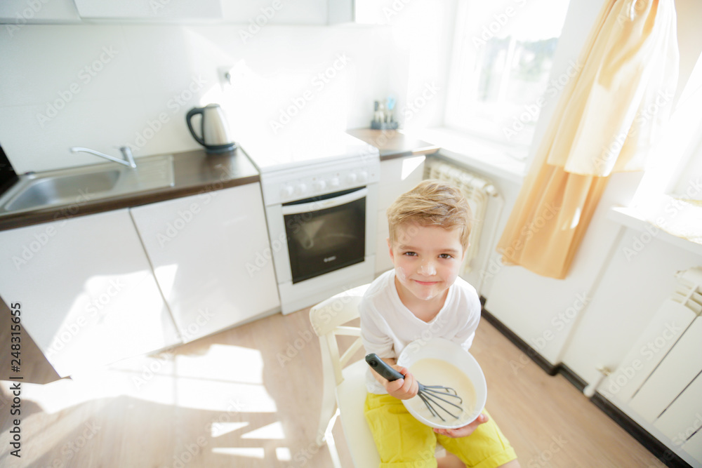 Sweet preschool child in the kitchen, making pancakes in the morning