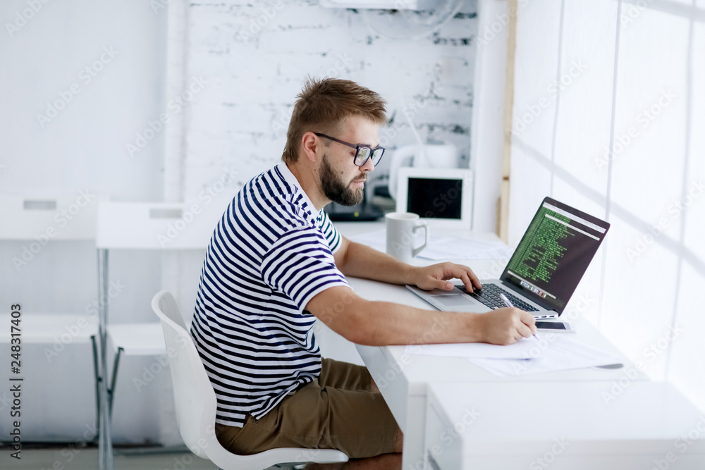 Young business man, sitting at desk at home and looking at open laptop display. Young business man, sitting at desk at home and looking at open laptop display.