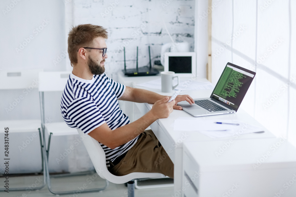 Freelancer man at work in office and looking at open laptop workstation. Freelancer man at work in office and looking at open laptop workstation.