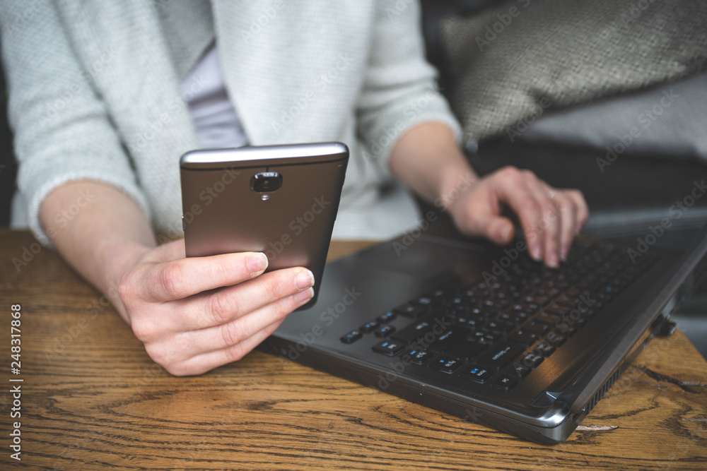 Woman using cellular and her modern laptop Woman using cellular and her modern laptop