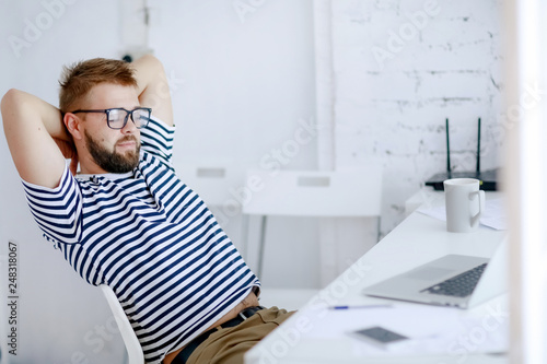 Successful businessman. Office worker. Portrait of bearded businessman. Serious businessman. Man standing at table and holds laptop. Handsome bearded office worker.