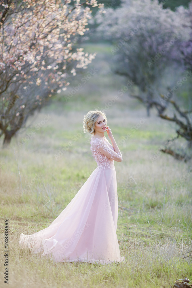 Beautiful girl wearing a bridal gown in a pink forest