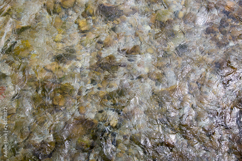 top view of pebble stones in fast-moving stream, abstract picture