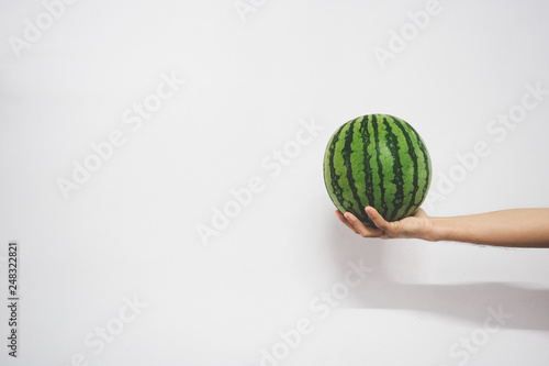 Closeup of hand holding watermelon against white background