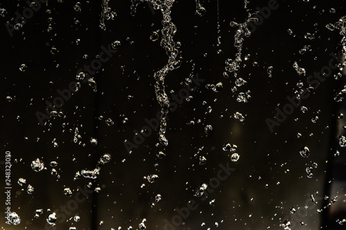 Water splash in dark with a drops of water flying, defocused bokeh.