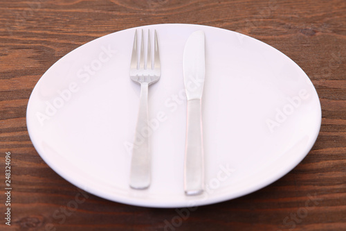 茶色い木製テーブルに置かれた白い皿とカトラリーによる食事終了の合図