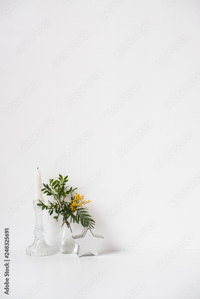 Fototapeta premium Small bouquet with green leaves and mimosa flowers and empty white wall