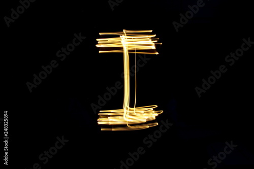 Long exposure, light painting photography.  Letter i in a vibrant neon metallic yellow gold colour against a black background.  Alphabet series.