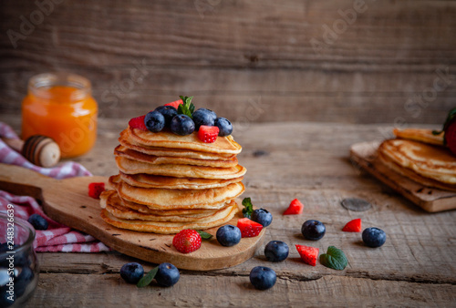 Pancakes with berries and maple syrup and sugar powder
