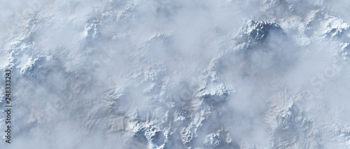 Aerial of rough steep snowy mountains in fog.