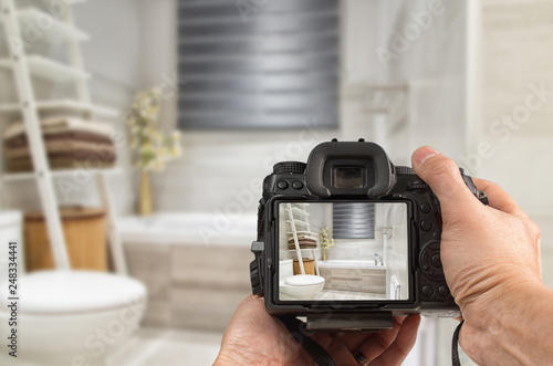 Hands holding DSLR capturing interior of a modern bathroom photo